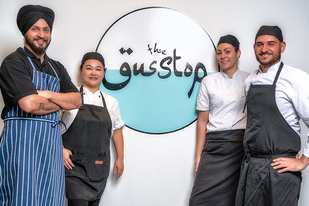 The Gusstop team of chefs standing in front of the Gusstop logo